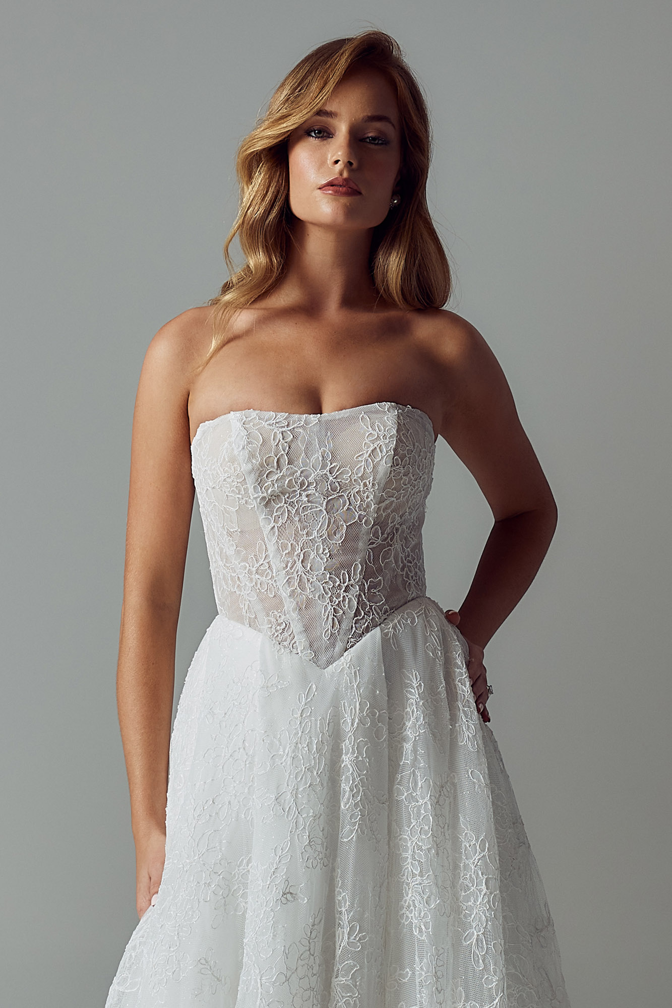 Brautkleid mit trägerloser transparenter Corsage, floraler Chantilly-Spitze, eingearbeiteten Stäbchen und spitzer Baskentaille